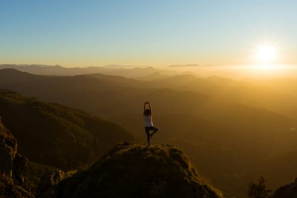 Person doing the yoga tree pose on a mountain